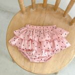 Baby girl wearing a dot-patterned cake ruffle skirt in white and pink, perfect for summer outings.