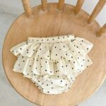 Baby girl wearing a dot-patterned cake ruffle skirt in white and pink, perfect for summer outings.