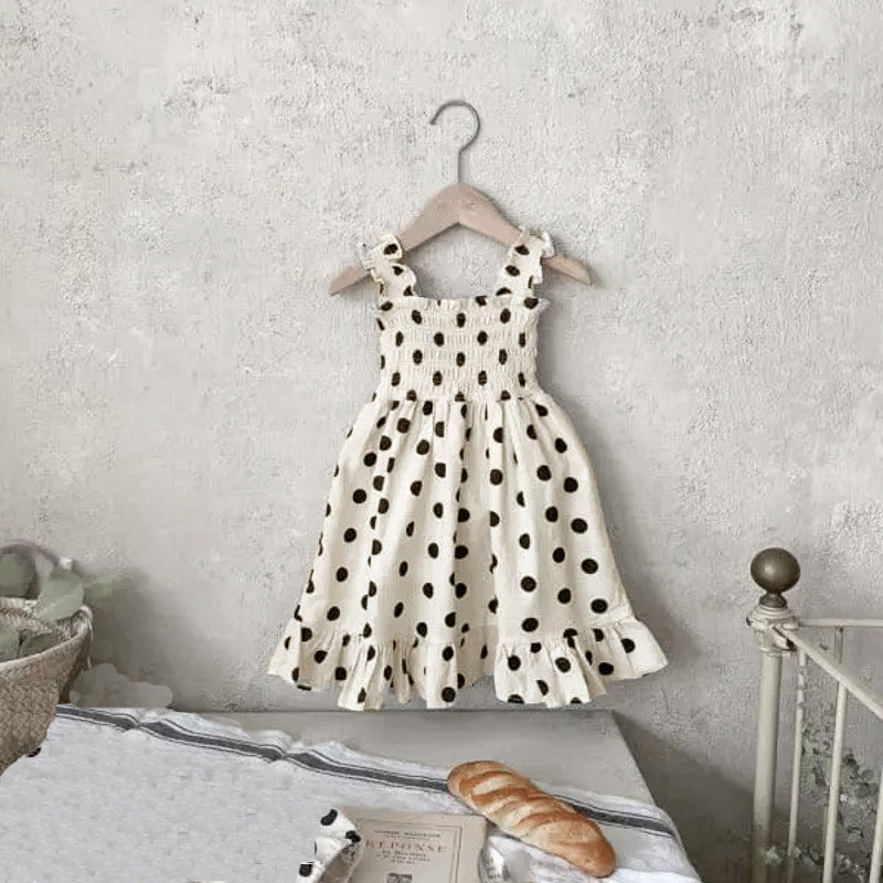 Baby girl wearing a beige and apricot polka dot sling onesie and dress, perfect for summer outings.