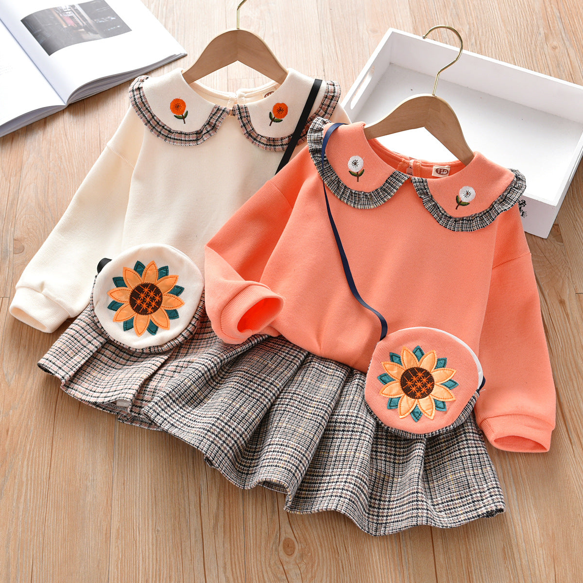 Baby girl wearing a floral patches doll neck pullover hoodie with a pleated skirt, showcasing a vintage style in orange and beige colors.