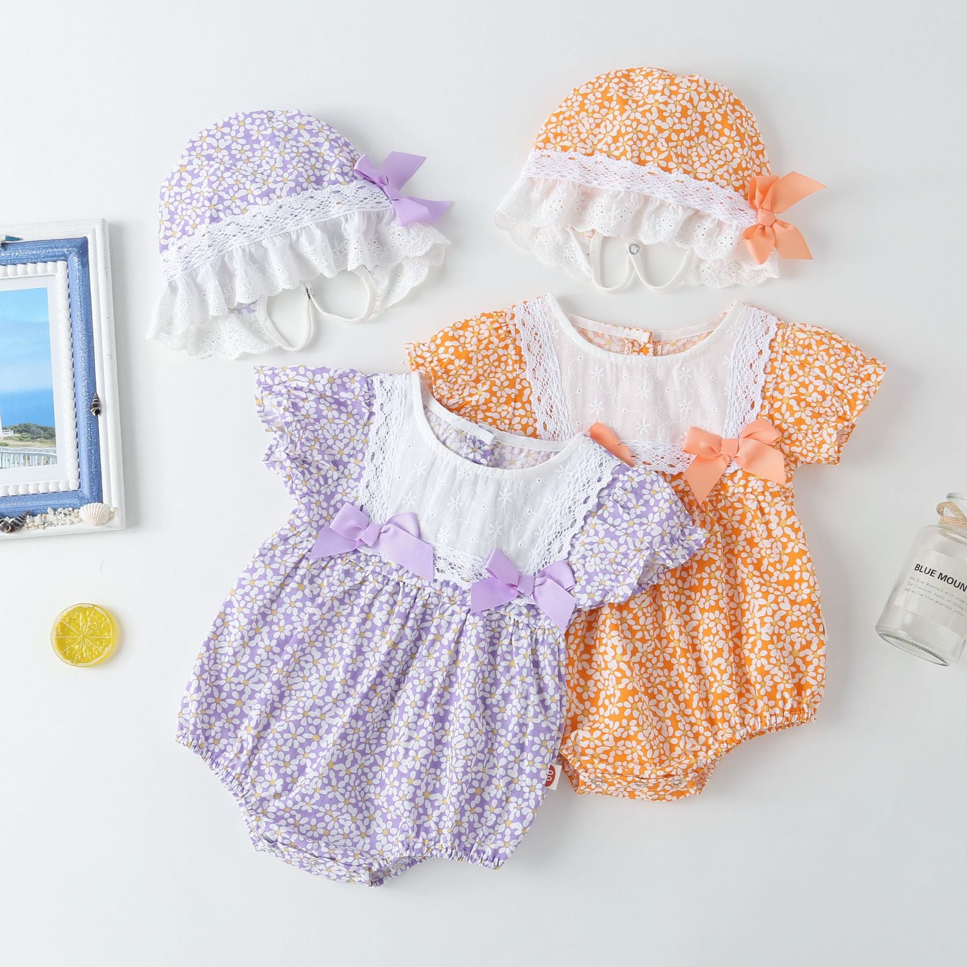 A vibrant baby girl onesie featuring a floral pattern and lace patchwork, with a round collar, in purple and orange colors.
