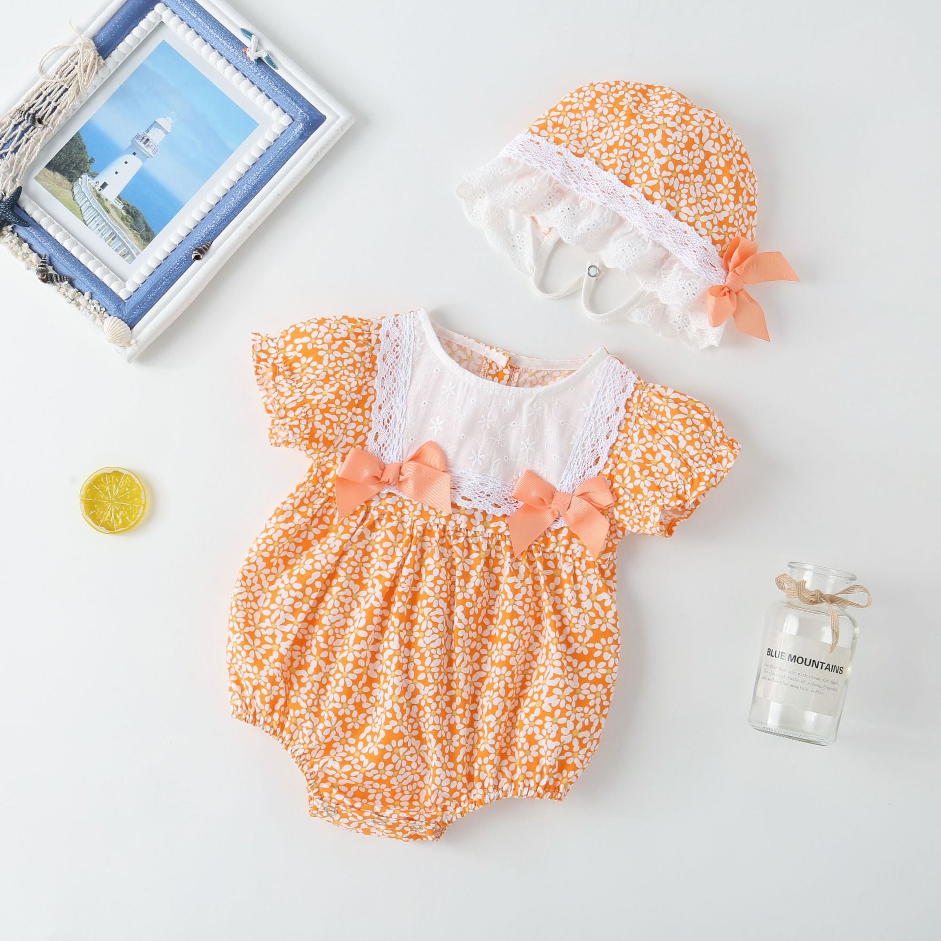 A vibrant baby girl onesie featuring a floral pattern and lace patchwork, with a round collar, in purple and orange colors.