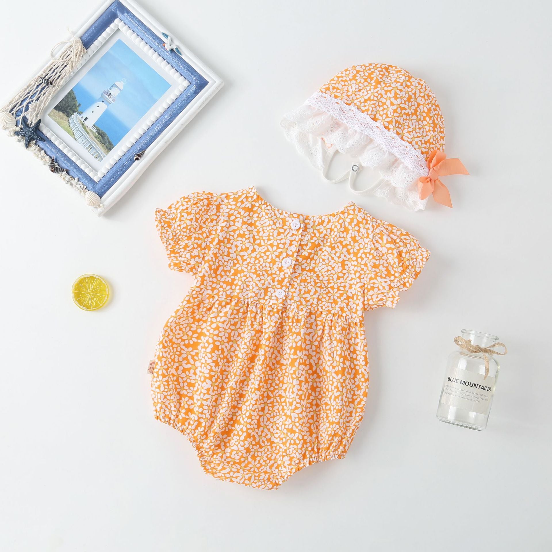 A vibrant baby girl onesie featuring a floral pattern and lace patchwork, with a round collar, in purple and orange colors.