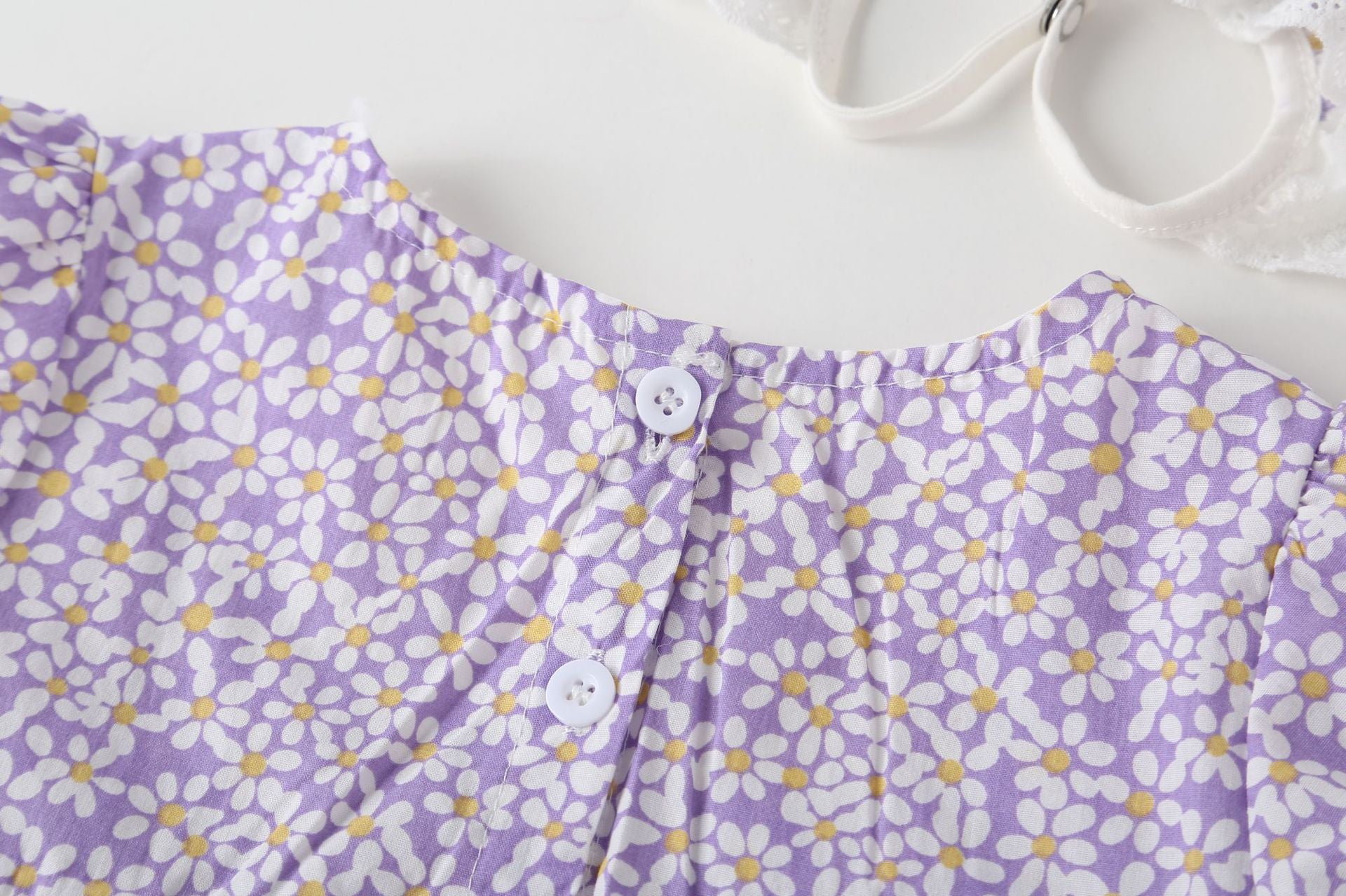 A vibrant baby girl onesie featuring a floral pattern and lace patchwork, with a round collar, in purple and orange colors.