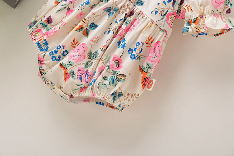 Baby girl wearing a floral pattern onesie with round collar and bubble sleeves, complemented by a matching hair rope with a bow.