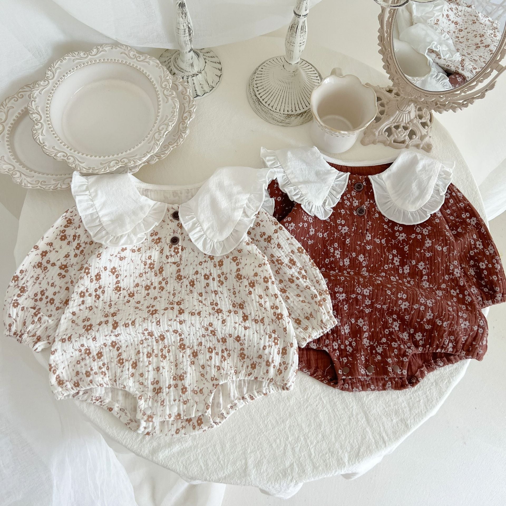 Baby girl bodysuit featuring a floral pattern with ruffle lapel design, made from soft cotton in white and brown colors.