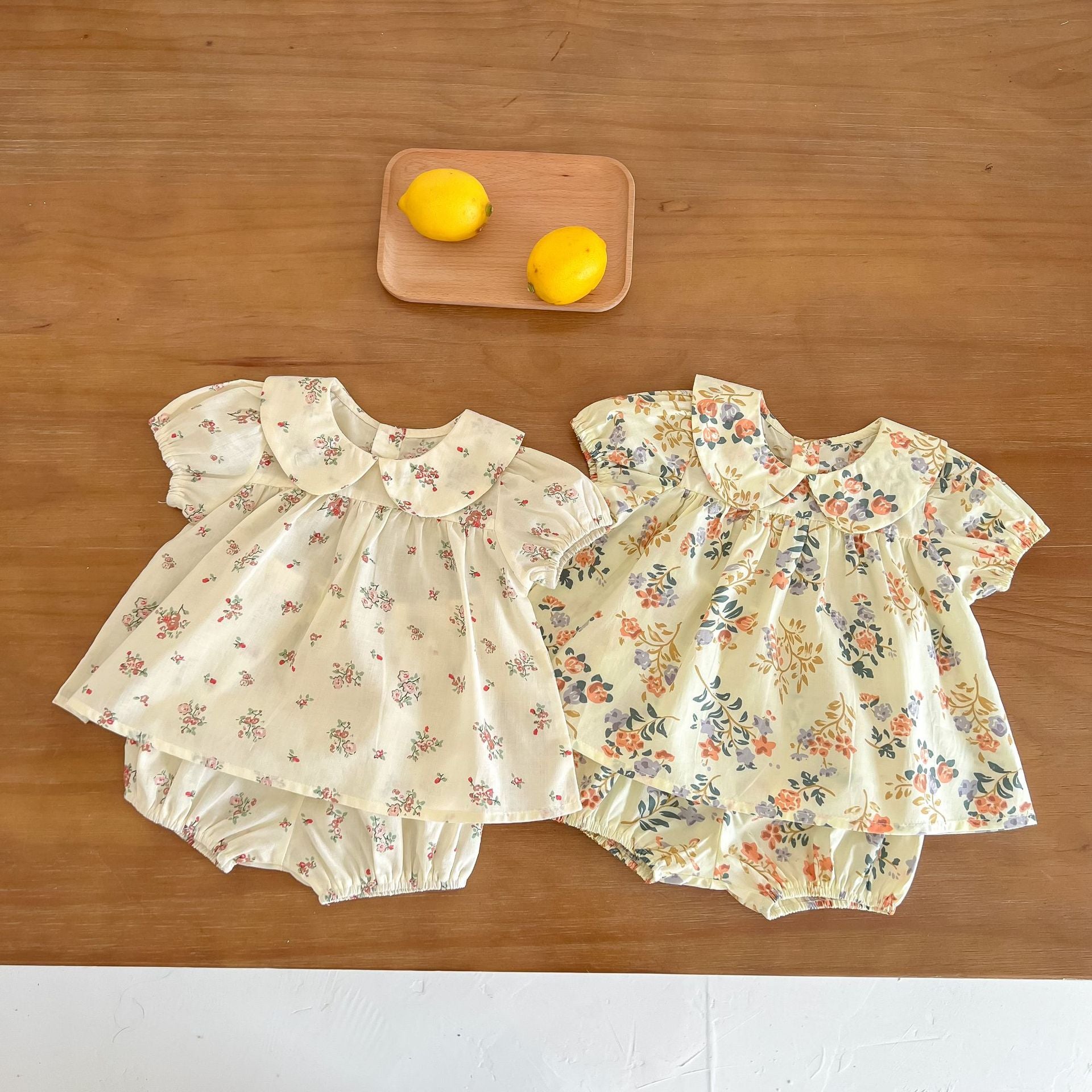 Baby girl wearing a floral print doll collar top and shorts set in white and yellow, perfect for summer outings.
