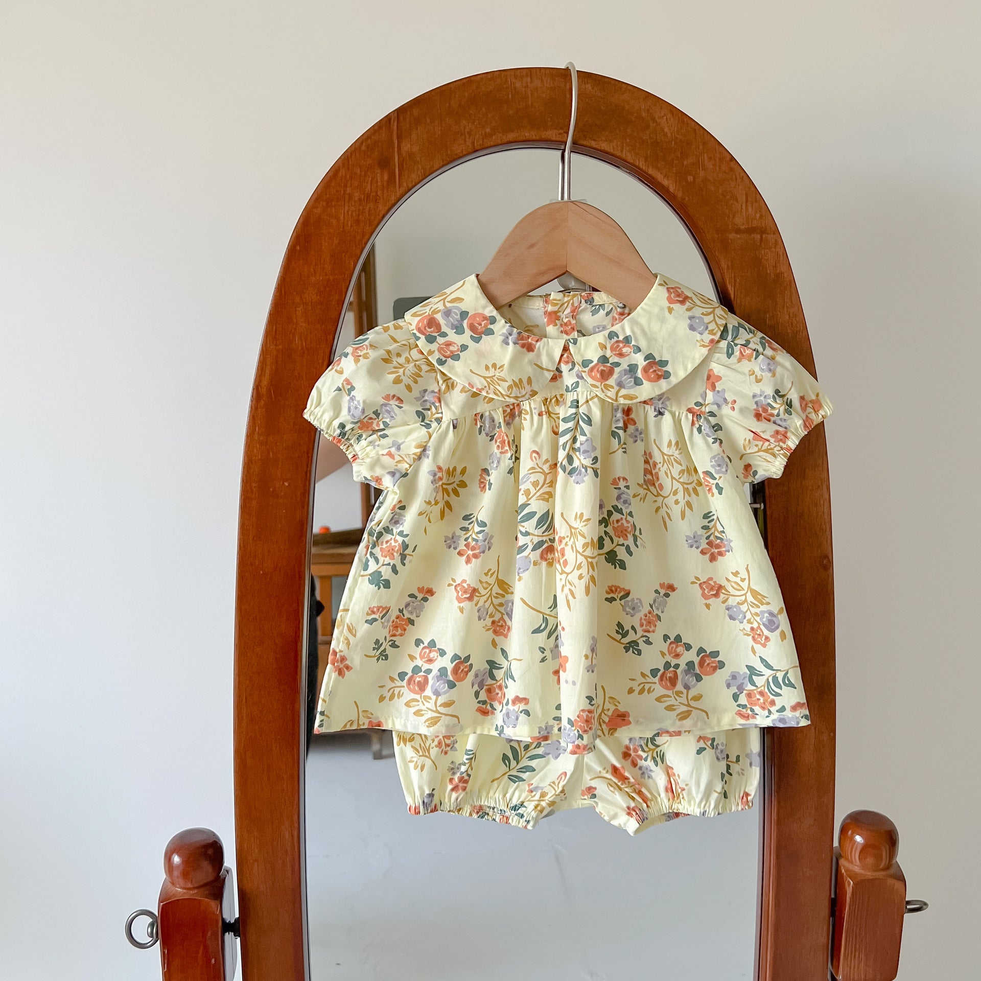 Baby girl wearing a floral print doll collar top and shorts set in white and yellow, perfect for summer outings.