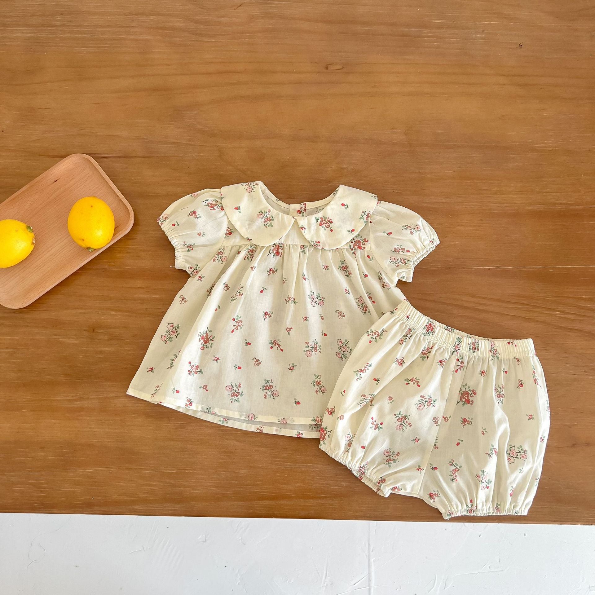 Baby girl wearing a floral print doll collar top and shorts set in white and yellow, perfect for summer outings.
