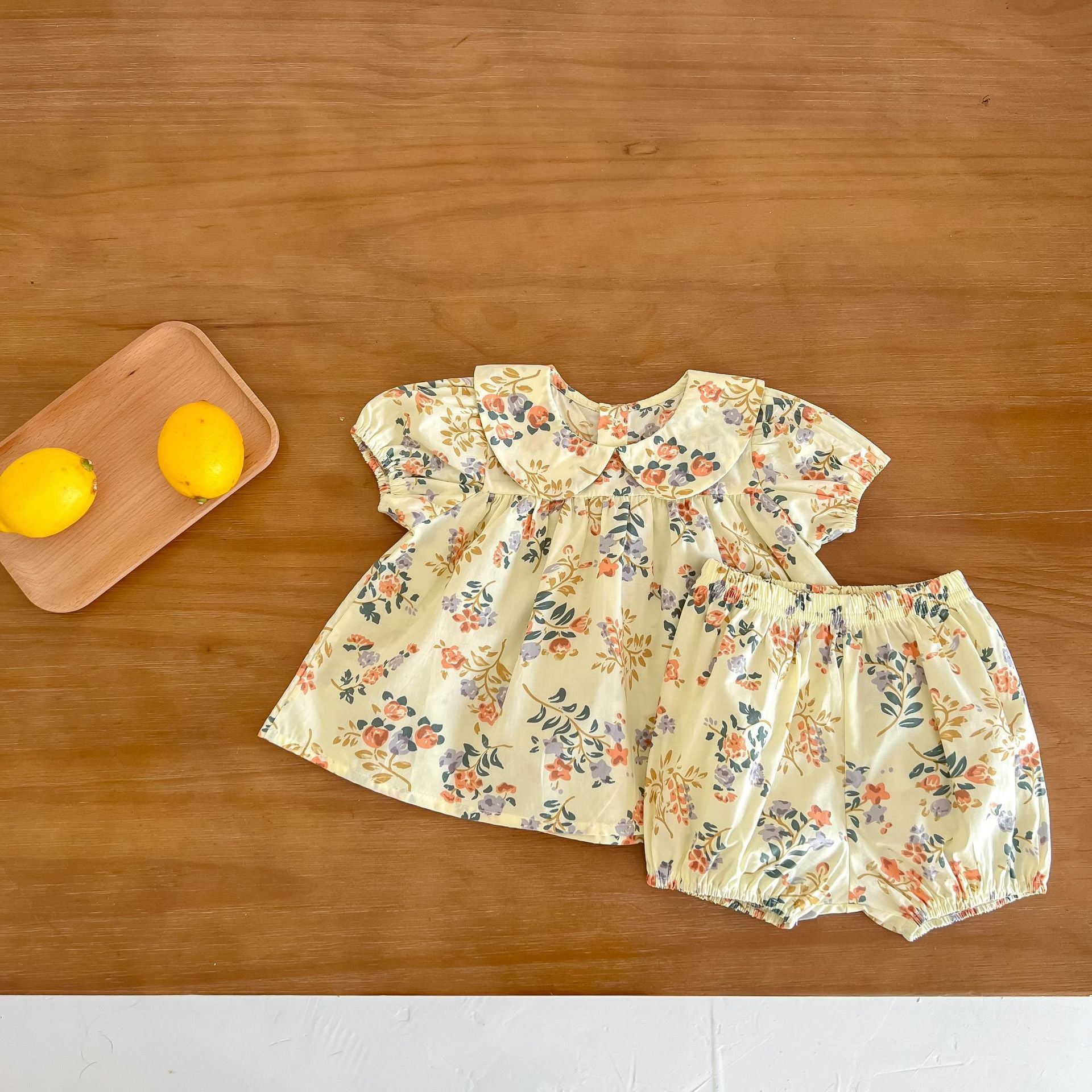 Baby girl wearing a floral print doll collar top and shorts set in white and yellow, perfect for summer outings.