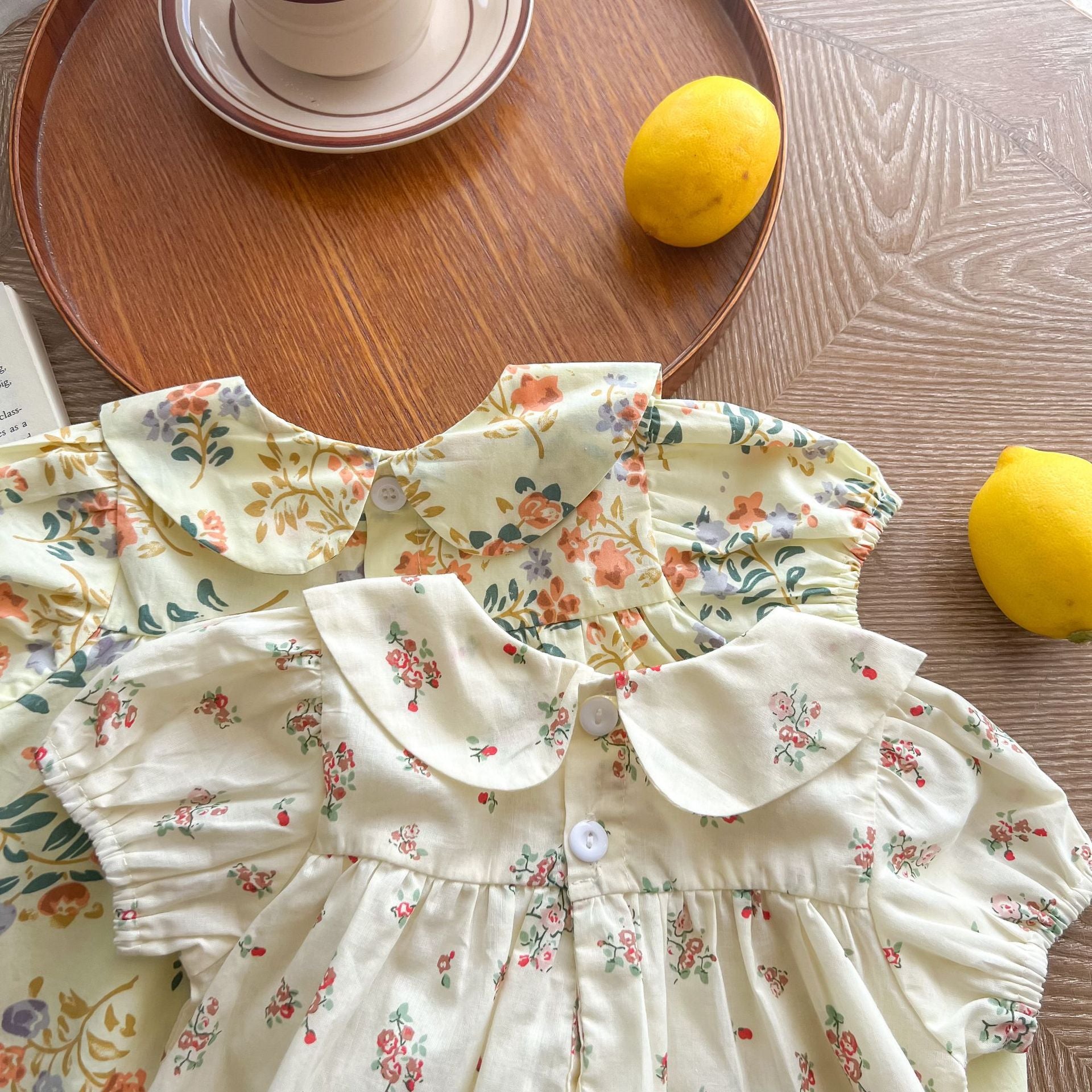 Baby girl wearing a floral print doll collar top and shorts set in white and yellow, perfect for summer outings.
