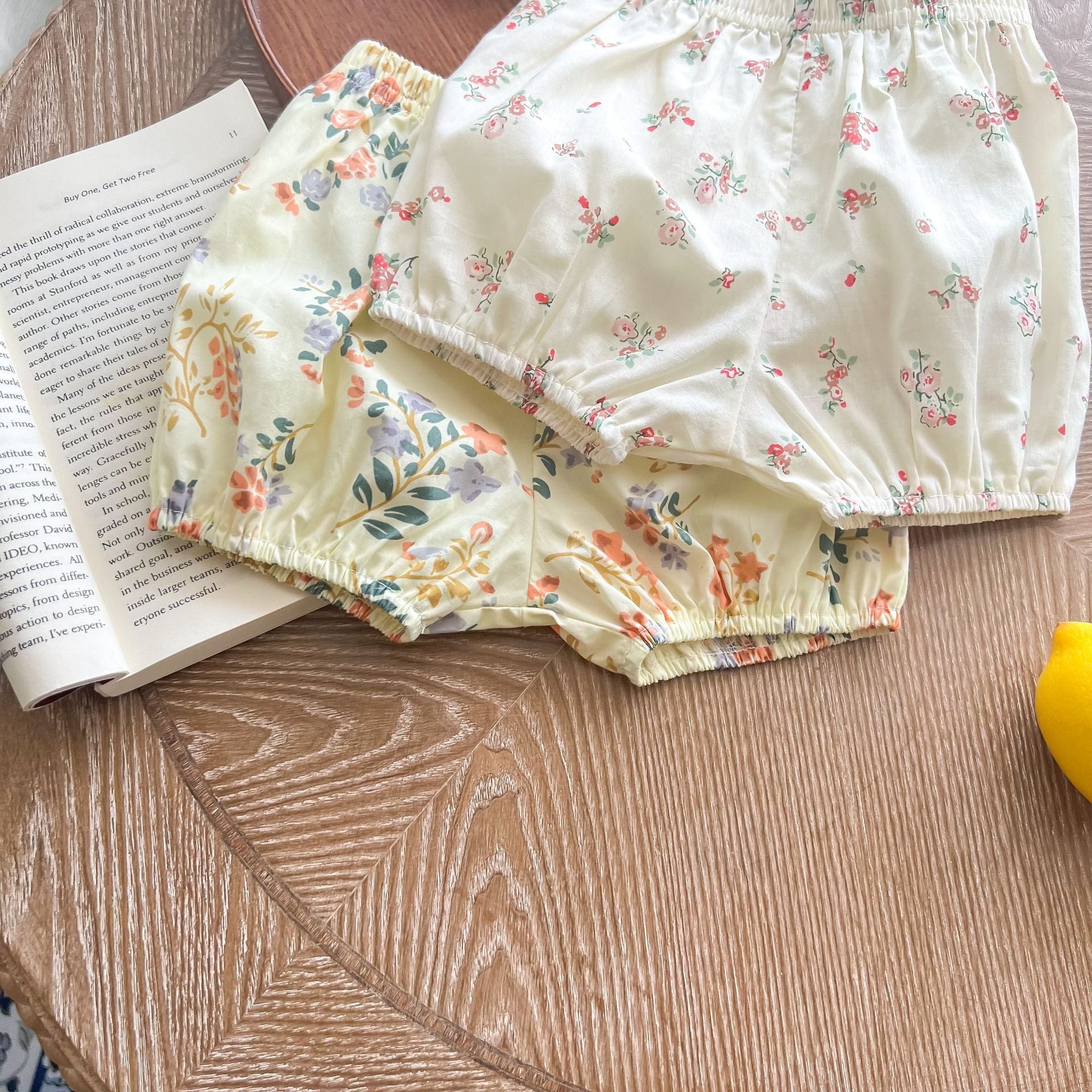 Baby girl wearing a floral print doll collar top and shorts set in white and yellow, perfect for summer outings.