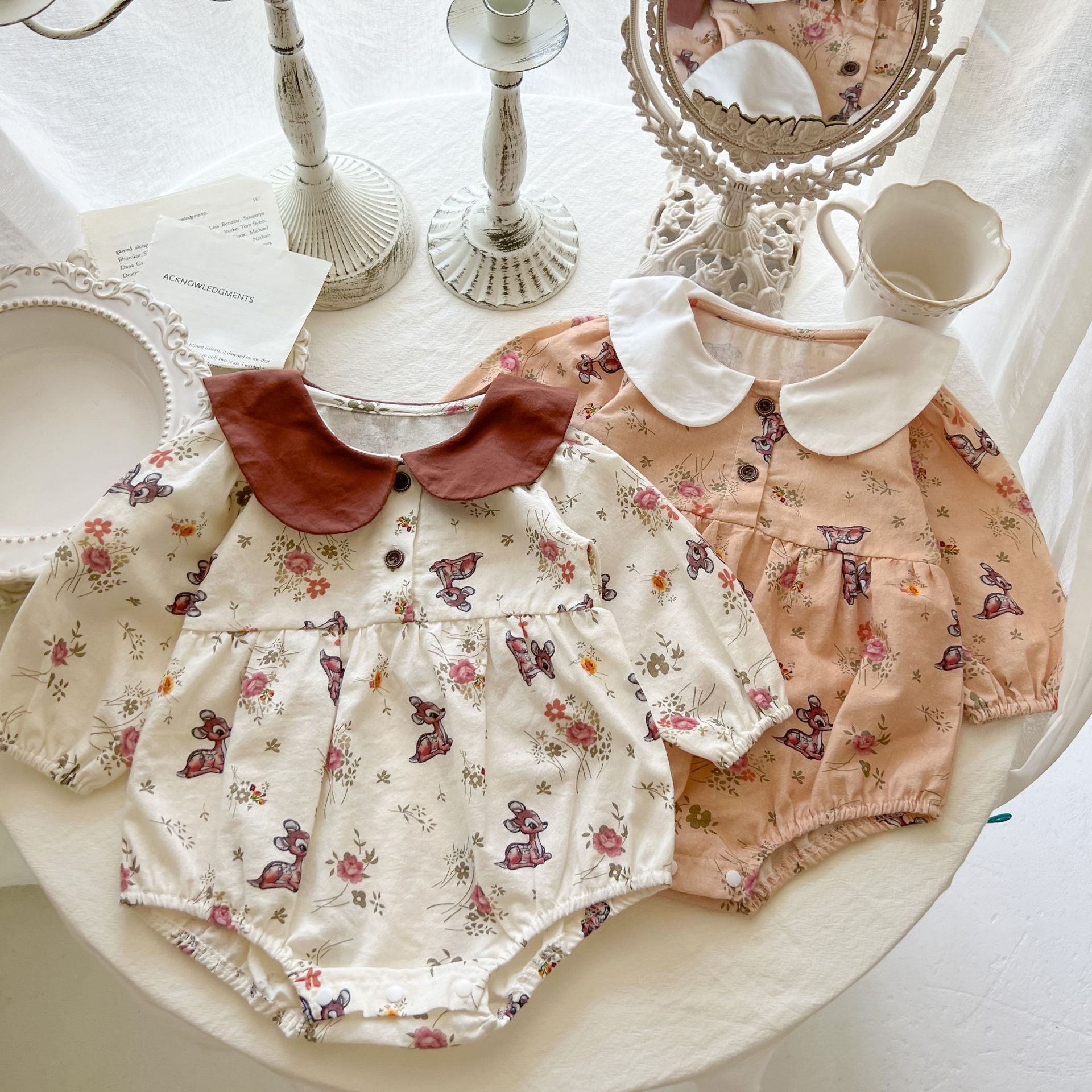 Baby girl cotton bodysuit featuring a doll neck design with floral and deer patterns in white and apricot colors.