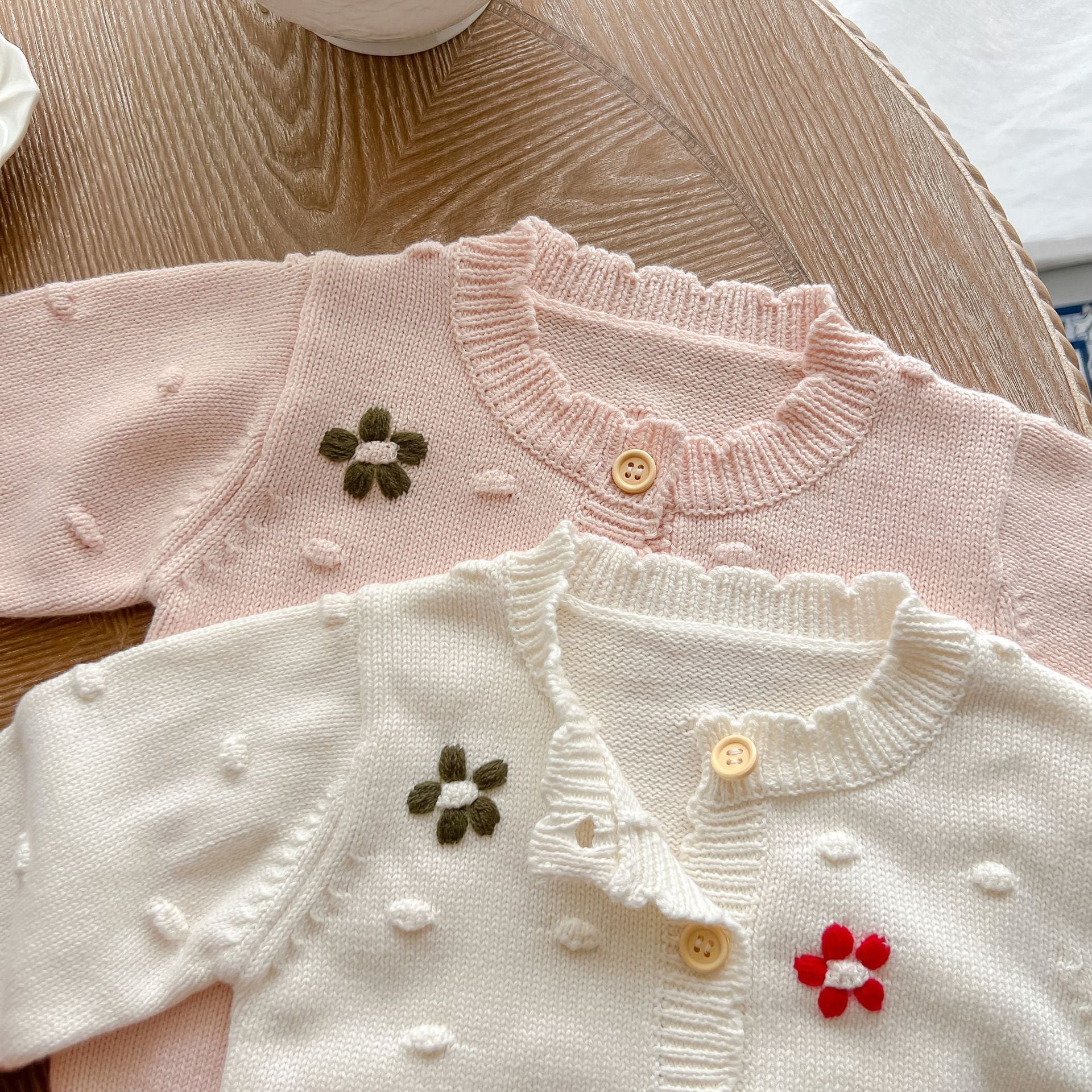 Baby girl cardigan featuring flower embroidery in white and pink colors, designed for comfort and style.