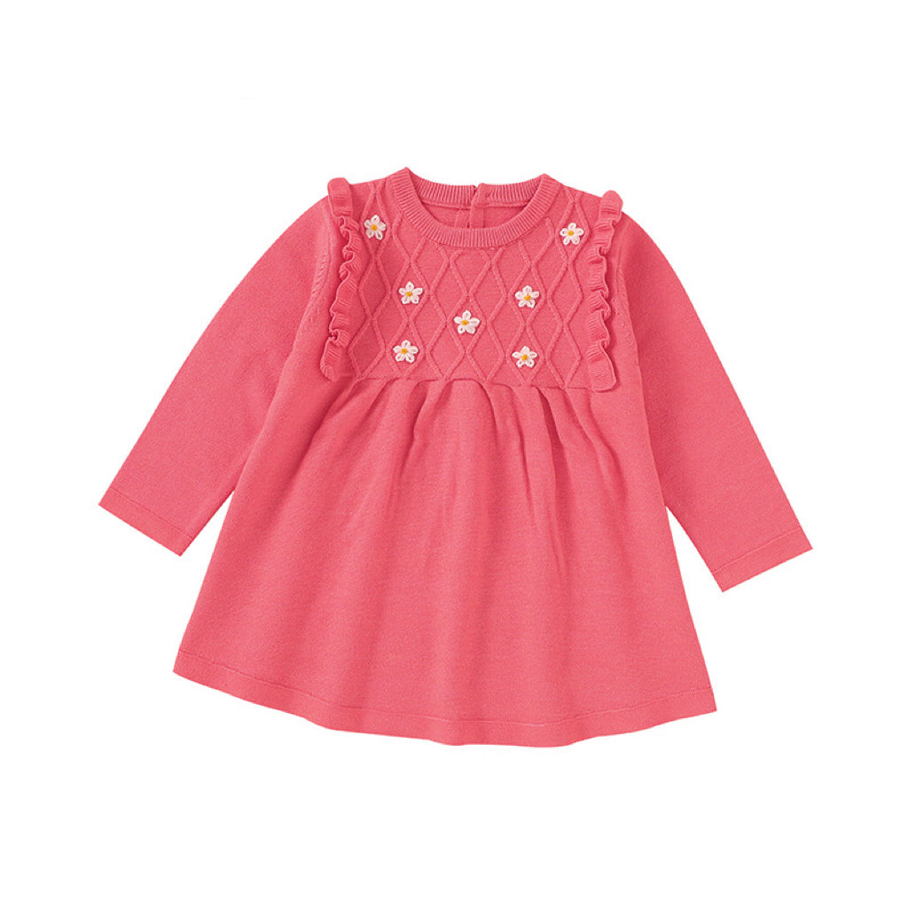 A baby girl wearing a soft knitted dress with flower patches in various colors, showcasing comfort and style.