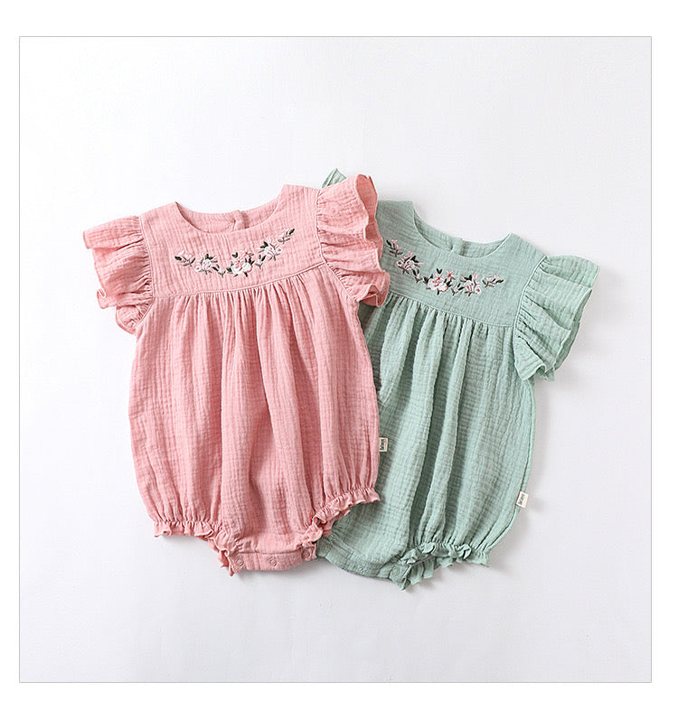 Baby girl onesie featuring floral patterns and flying sleeves in pink and green colors, made from soft cotton material.