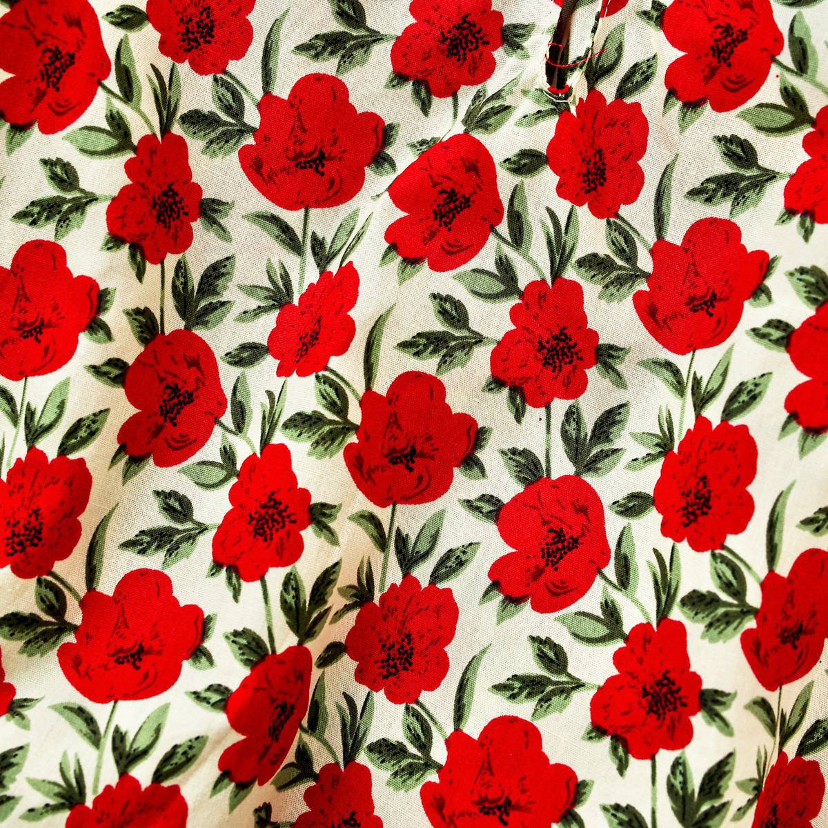 A baby girl wearing a flower-patterned bodysuit with a labeled collar and long sleeves in vibrant red and yellow colors.