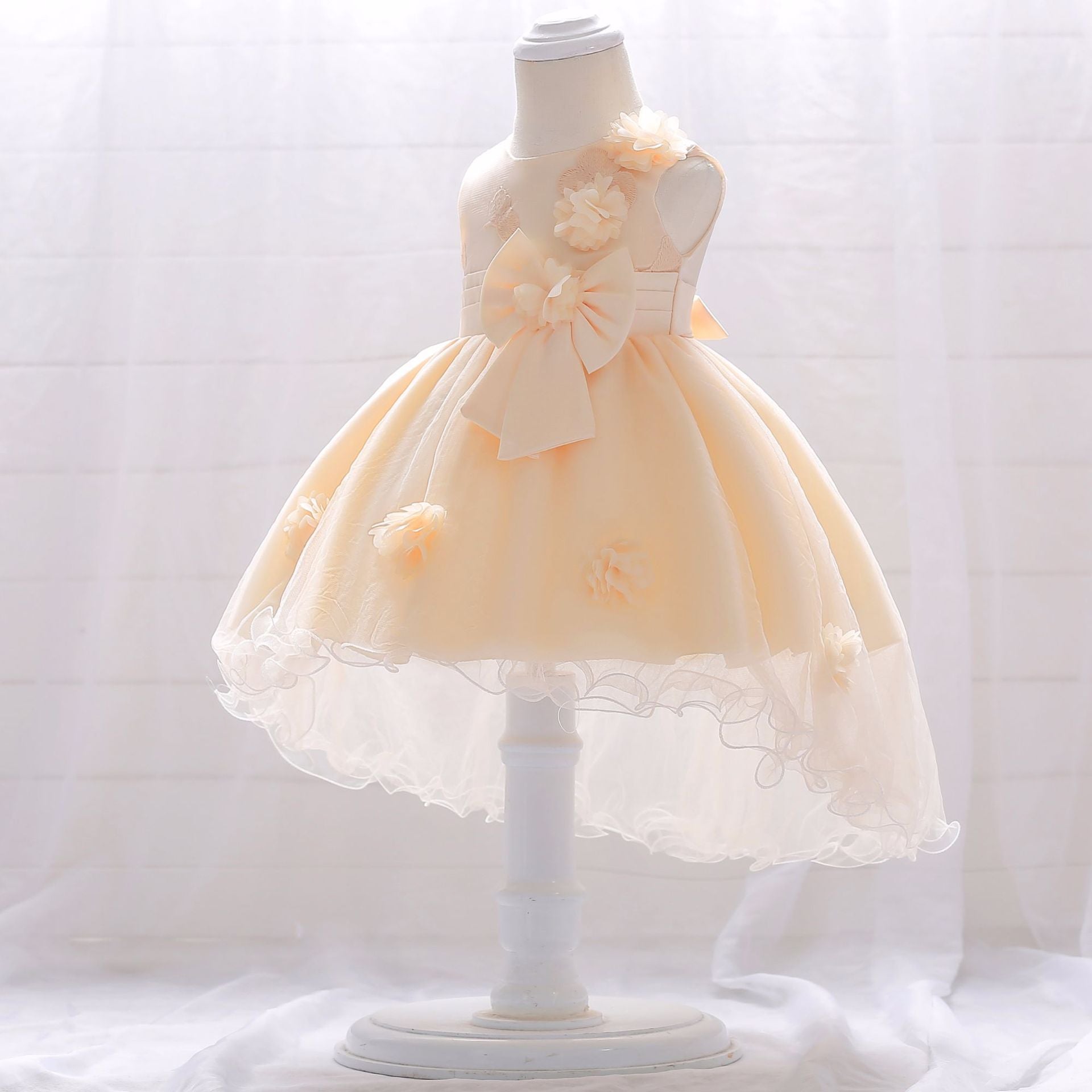 Baby girl wearing a Full Moon Christening Trailing Tutu Formal Dress in white, showcasing delicate tulle fabric and a graceful trailing skirt.