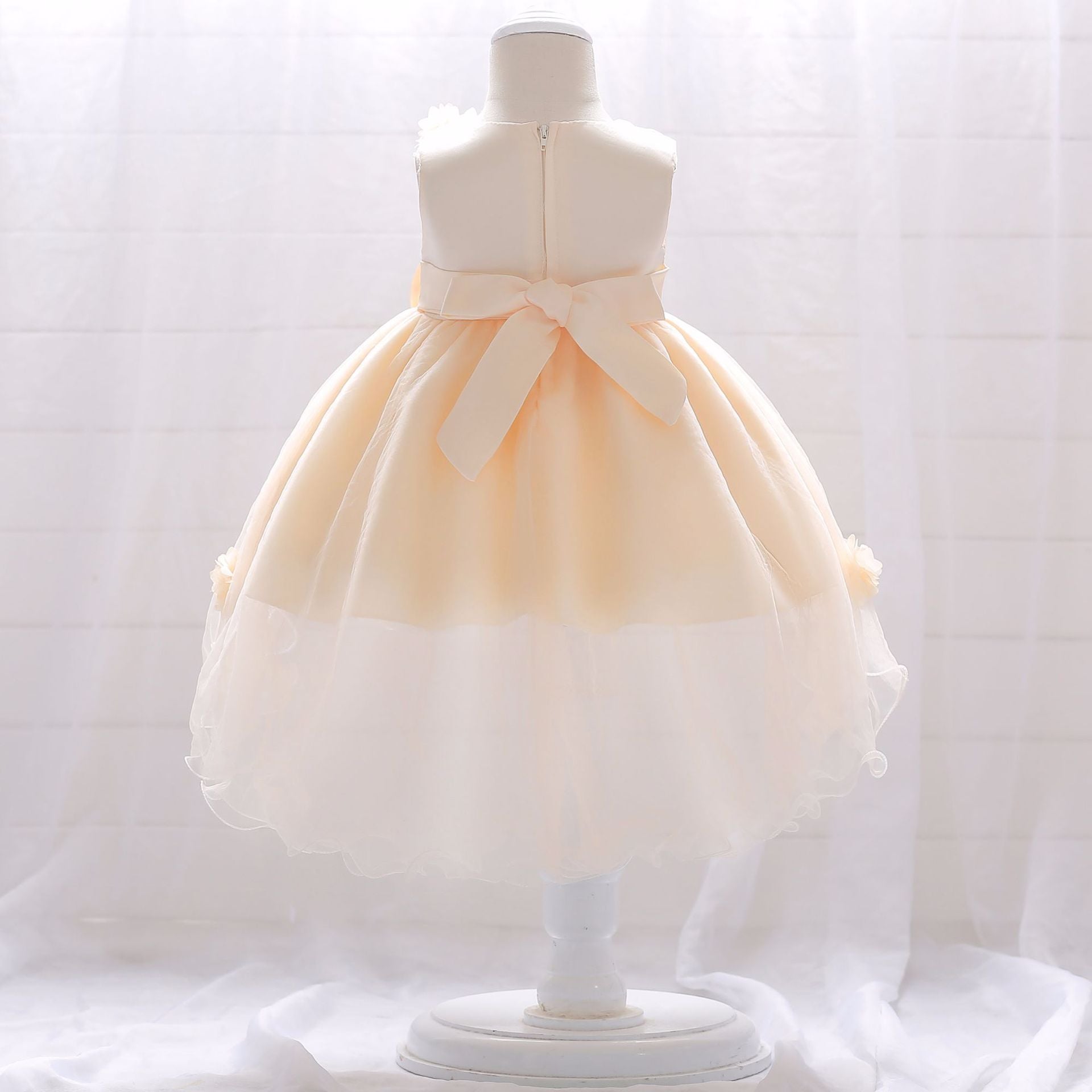 Baby girl wearing a Full Moon Christening Trailing Tutu Formal Dress in white, showcasing delicate tulle fabric and a graceful trailing skirt.