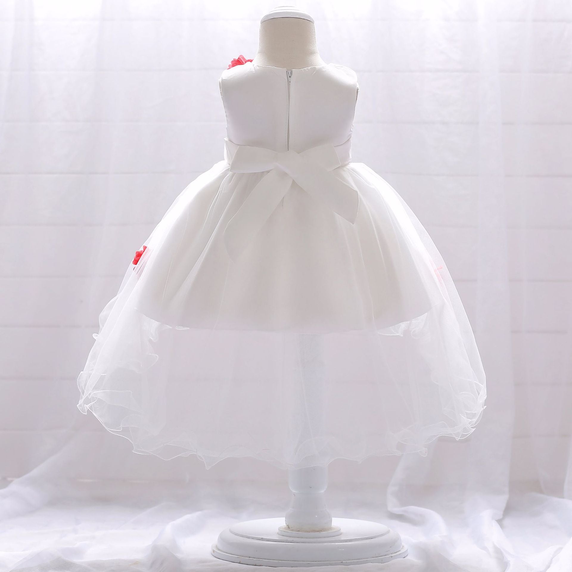 Baby girl wearing a Full Moon Christening Trailing Tutu Formal Dress in white, showcasing delicate tulle fabric and a graceful trailing skirt.