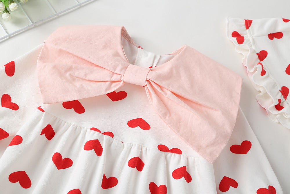 Baby girl onesie featuring a heart pattern and big bow tie, designed for comfort and style.