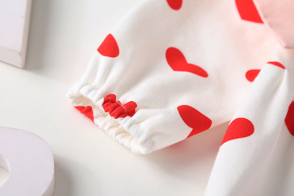 Baby girl onesie featuring a heart pattern and big bow tie, designed for comfort and style.