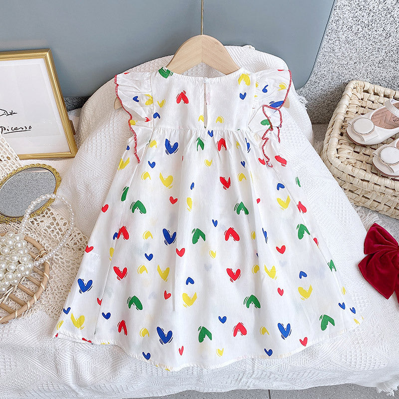 Baby girl wearing a white heart print ruffle dress, showcasing a charming design perfect for summer occasions.