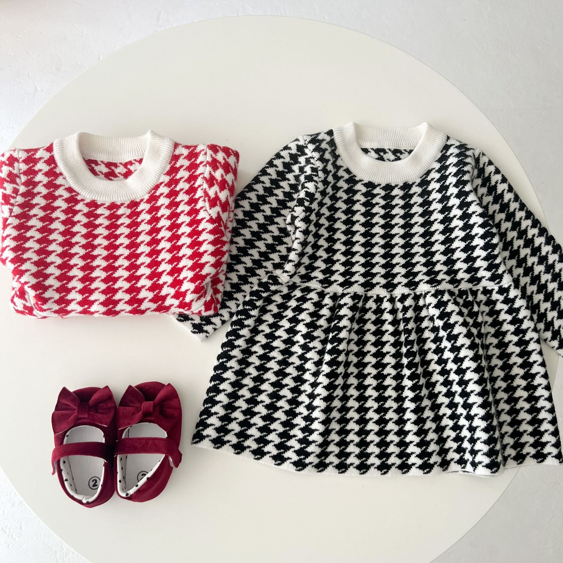 A stylish baby girl dress featuring a classic hounds tooth pattern, long sleeves, and a loose fit, available in black and red colors.