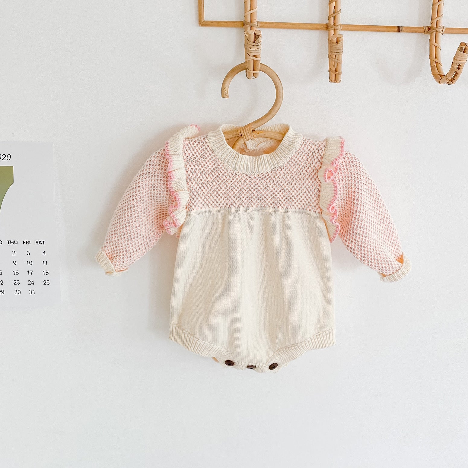 Baby girl knitted onesie in pink with ruffle design and contrast pattern, perfect for spring and autumn wear.