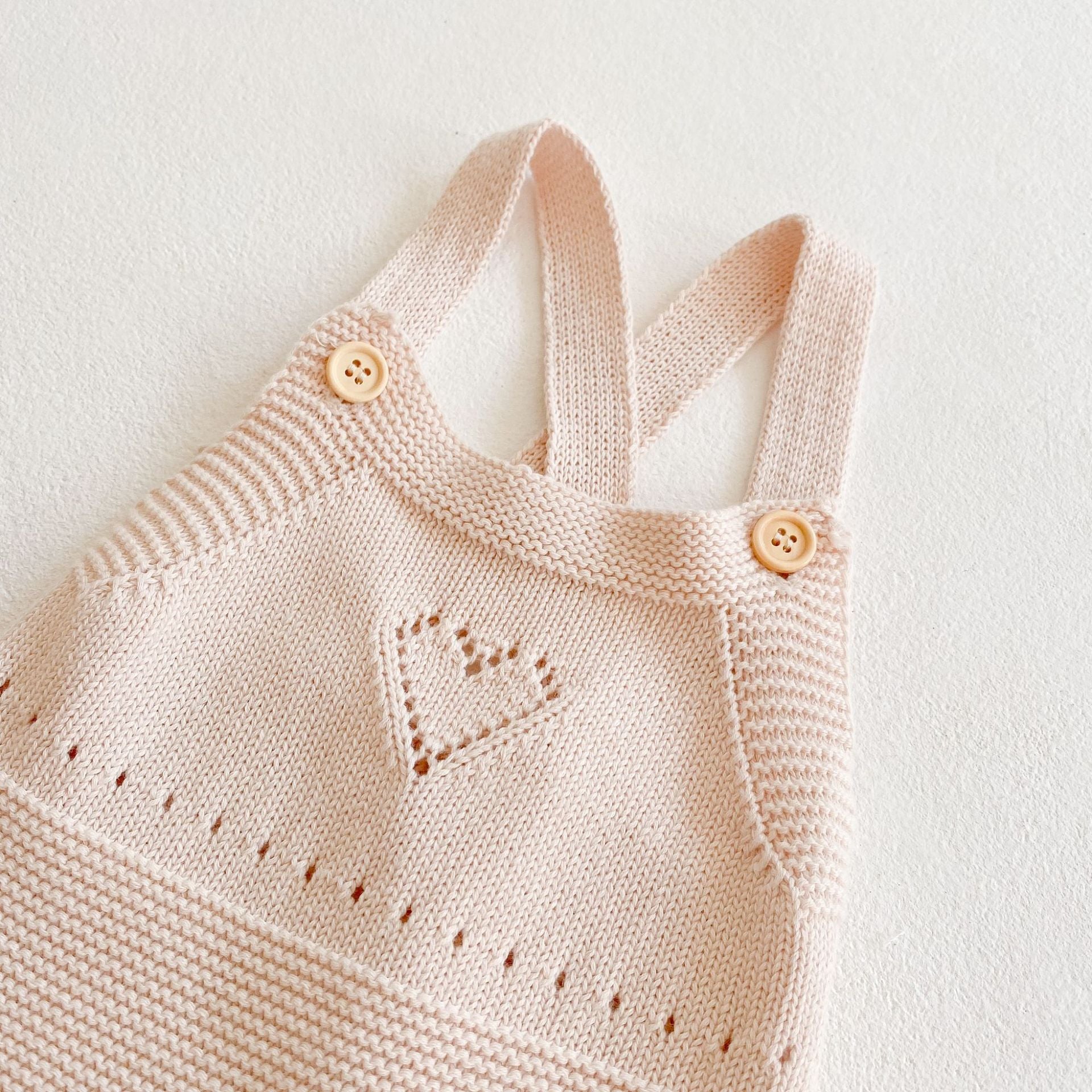 Baby girl knitted onesie in pink with ruffle design and contrast pattern, perfect for spring and autumn wear.