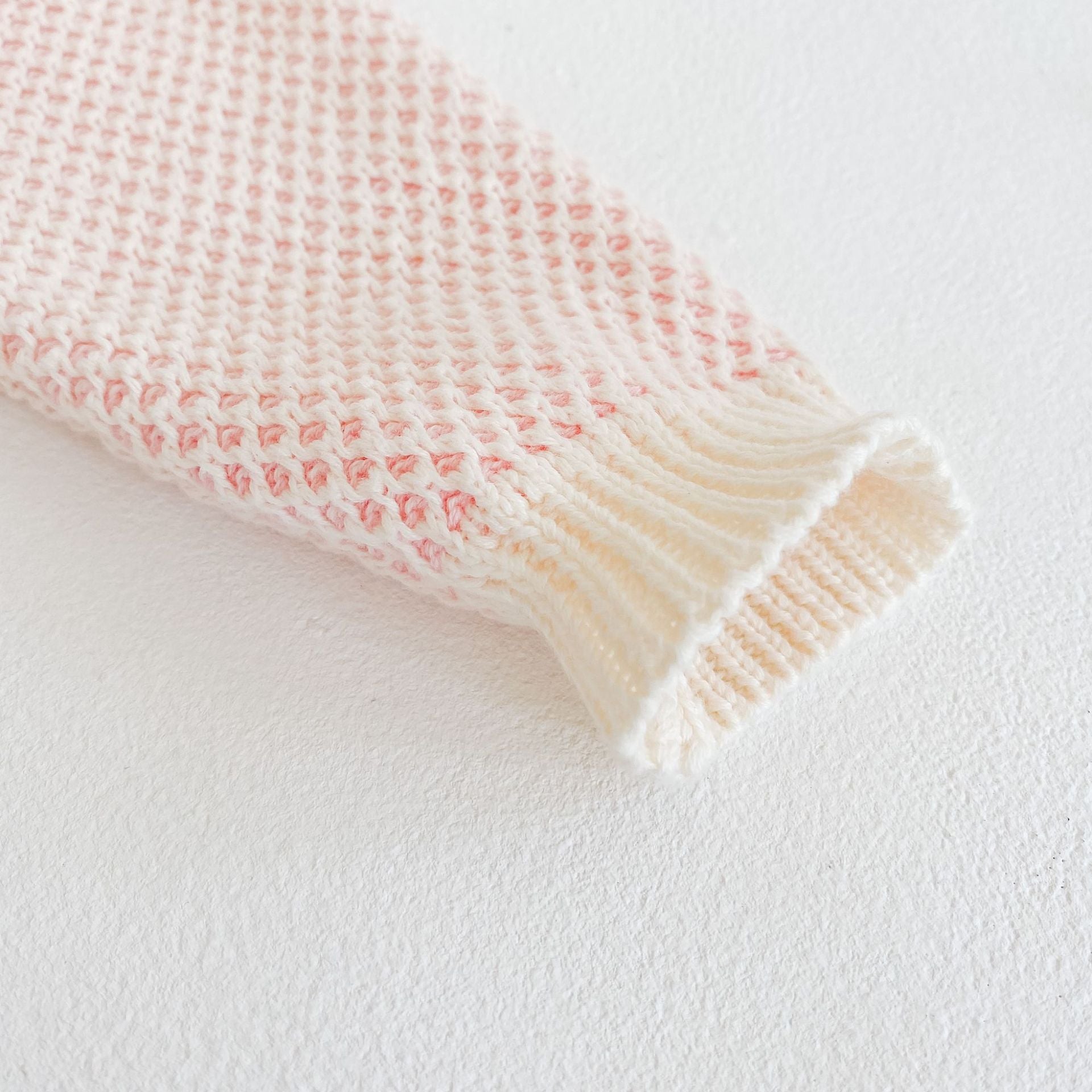 Baby girl knitted onesie in pink with ruffle design and contrast pattern, perfect for spring and autumn wear.