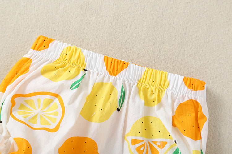 Baby girl wearing a lemon fruit print sleeveless dress combo with short pants, showcasing vibrant colors and a playful design.