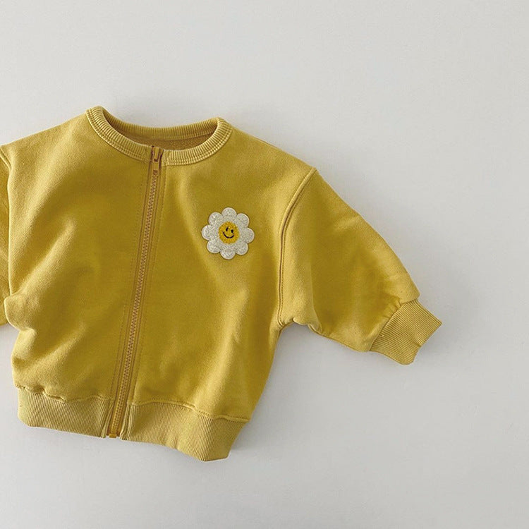 A cute baby girl wearing a cotton coat with sunflower patches and a zipper front design, perfect for autumn and winter.