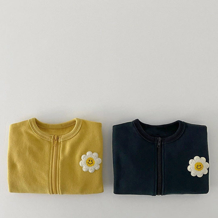 A cute baby girl wearing a cotton coat with sunflower patches and a zipper front design, perfect for autumn and winter.