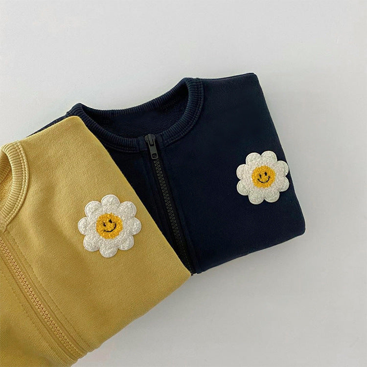 A cute baby girl wearing a cotton coat with sunflower patches and a zipper front design, perfect for autumn and winter.
