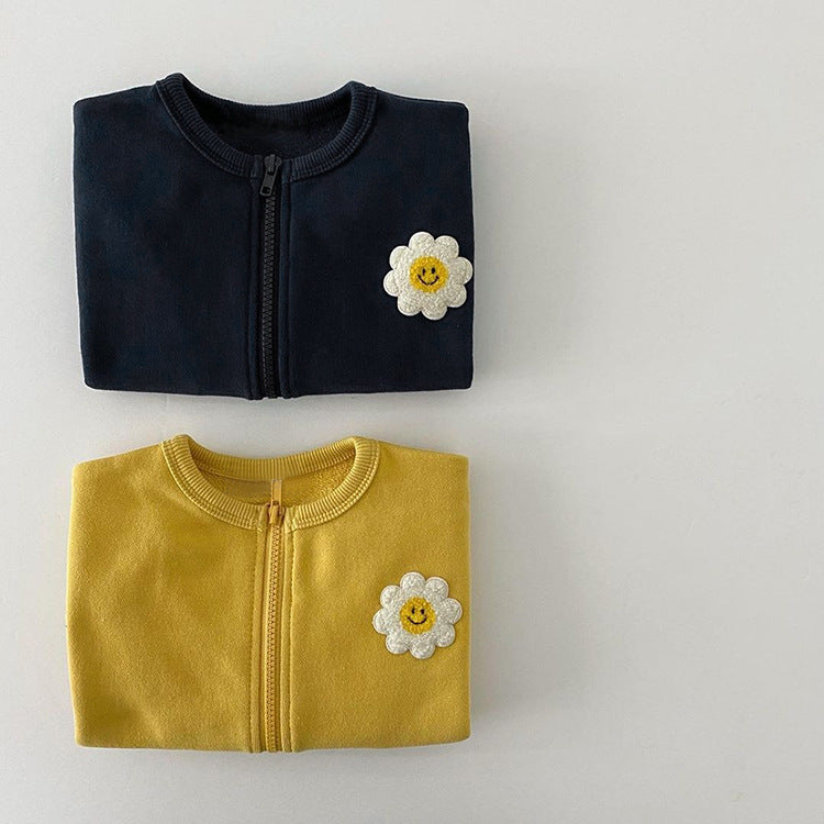 A cute baby girl wearing a cotton coat with sunflower patches and a zipper front design, perfect for autumn and winter.