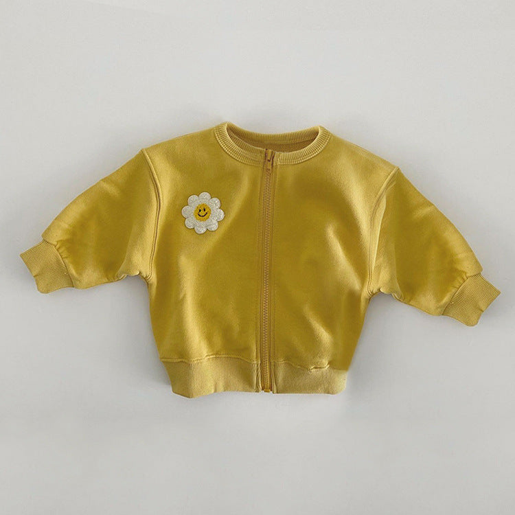 A cute baby girl wearing a cotton coat with sunflower patches and a zipper front design, perfect for autumn and winter.
