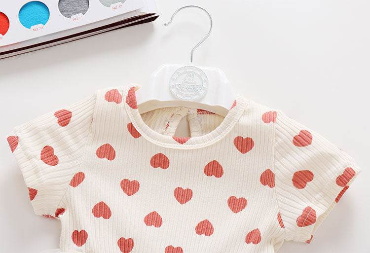 Baby girl onesie dress featuring mesh patchwork design and small heart print pattern in beige color.