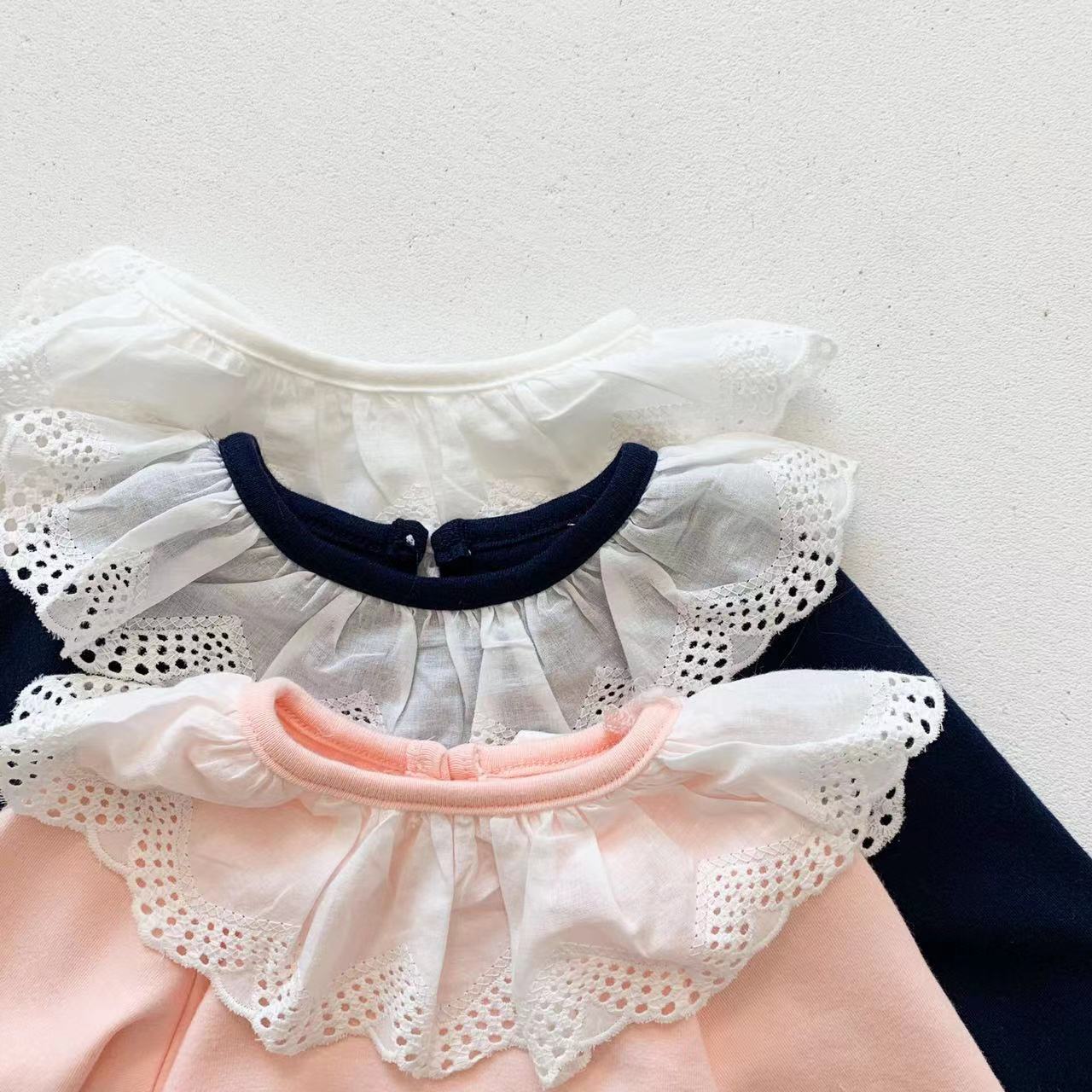 Adorable baby girl wearing a mesh ruffle neck long sleeved onesie in solid color, showcasing comfort and style.