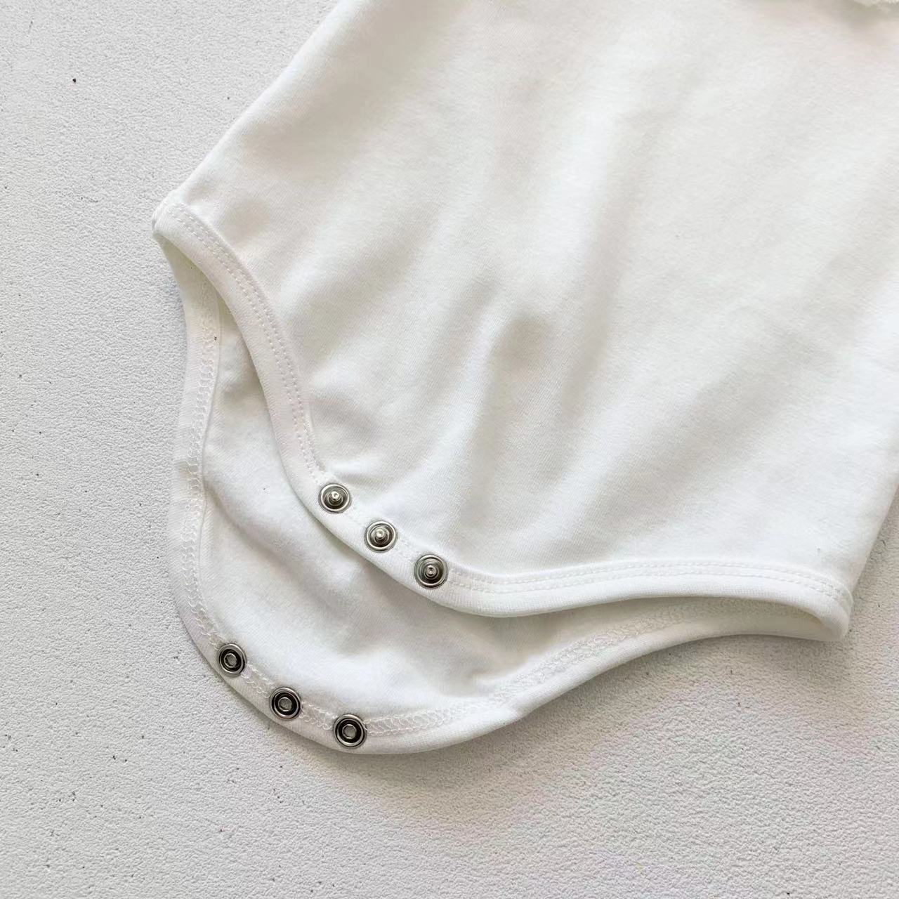 Adorable baby girl wearing a mesh ruffle neck long sleeved onesie in solid color, showcasing comfort and style.