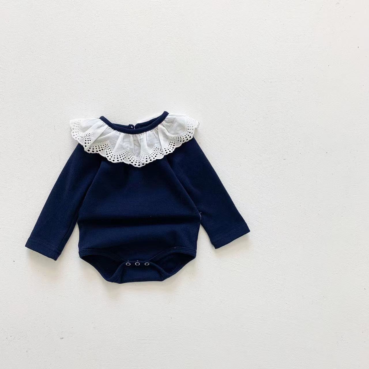 Adorable baby girl wearing a mesh ruffle neck long sleeved onesie in solid color, showcasing comfort and style.