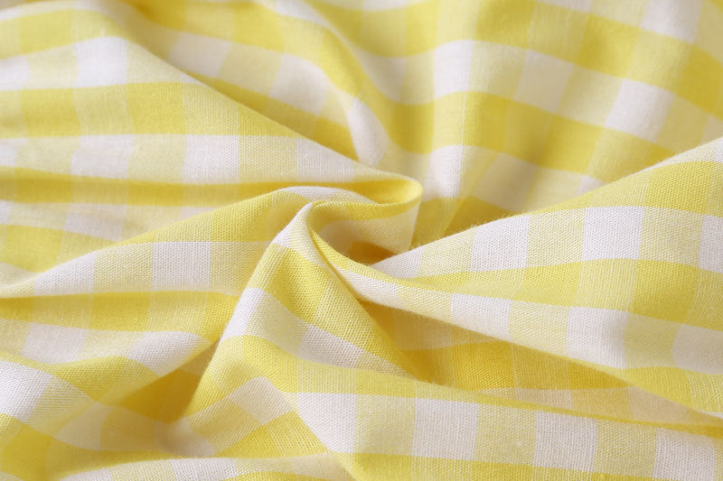 Baby girl sleeveless onesie featuring plaid pattern, lace patchwork, and bow in vibrant yellow color.