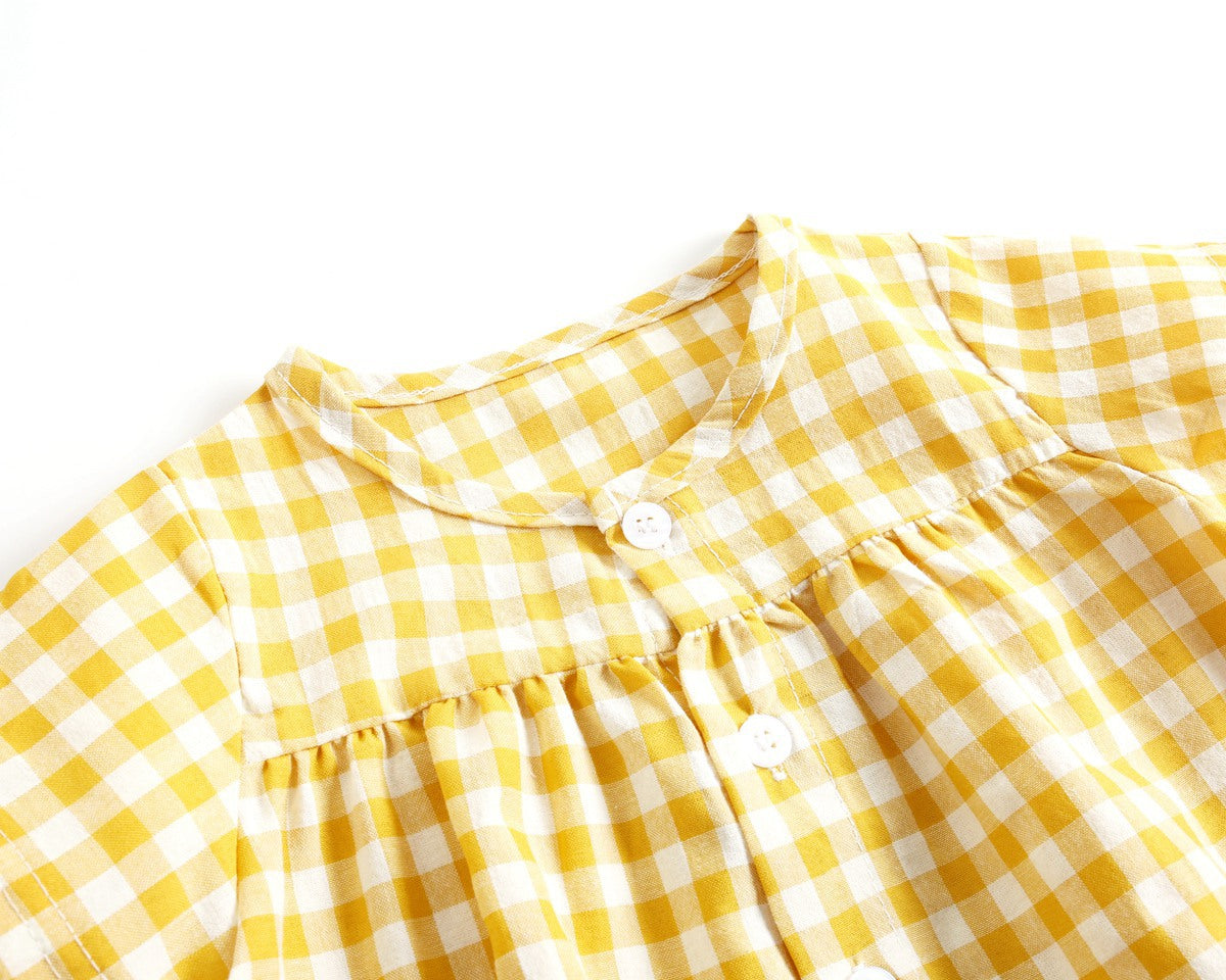 Baby girl wearing a plaid pattern shirt and shorts set in black and yellow, perfect for summer outings.