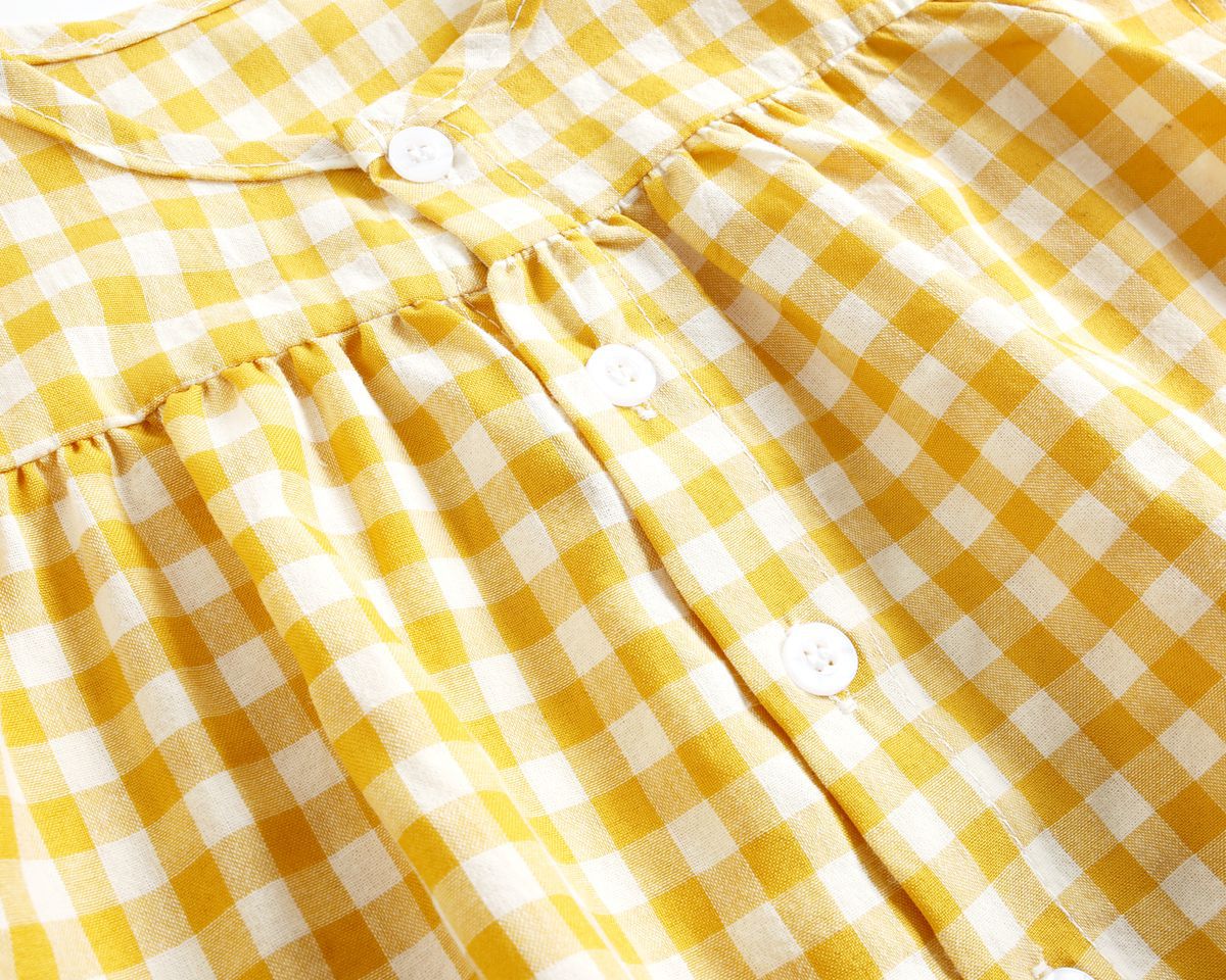 Baby girl wearing a plaid pattern shirt and shorts set in black and yellow, perfect for summer outings.
