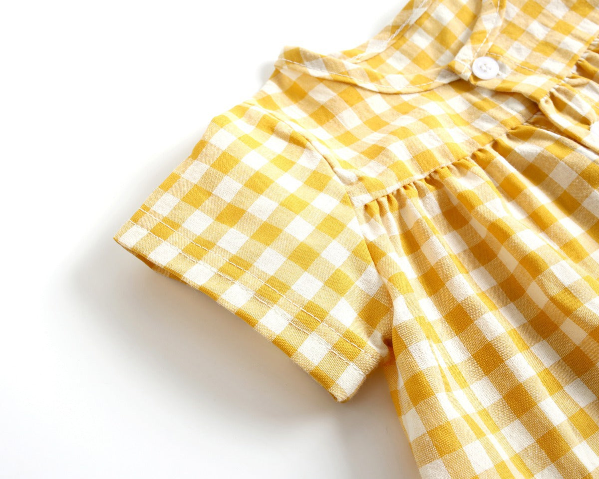 Baby girl wearing a plaid pattern shirt and shorts set in black and yellow, perfect for summer outings.