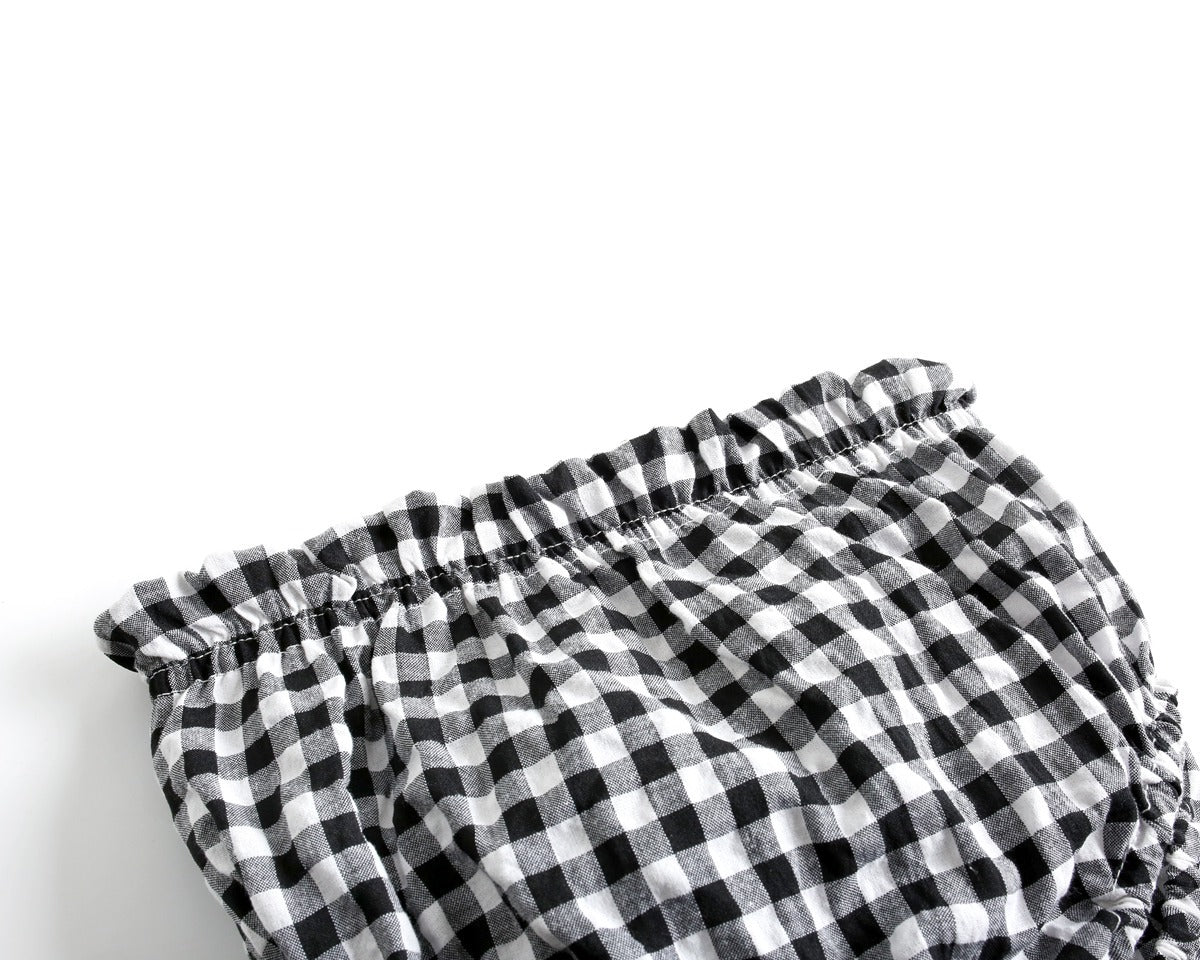 Baby girl wearing a plaid pattern shirt and shorts set in black and yellow, perfect for summer outings.