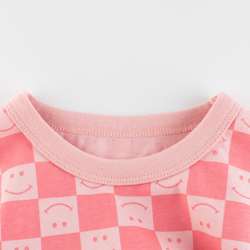 Baby girl wearing a pink plaid pattern t-shirt with a smiley face print, perfect for summer outings.