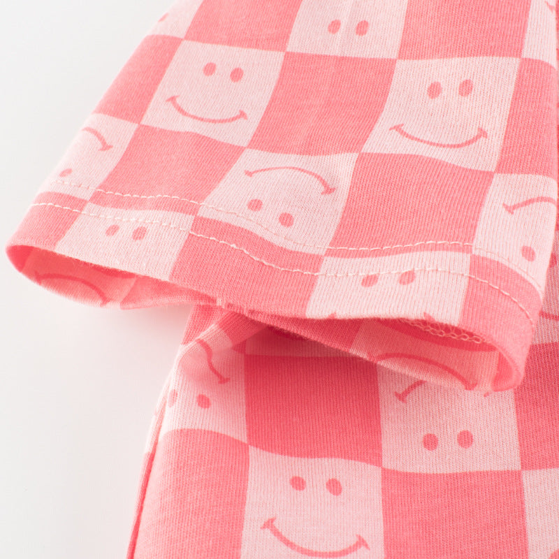 Baby girl wearing a pink plaid pattern t-shirt with a smiley face print, perfect for summer outings.
