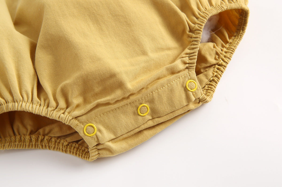 Baby girl wearing a stylish yellow polka dot onesie with a doll collar design and backless long sleeves.