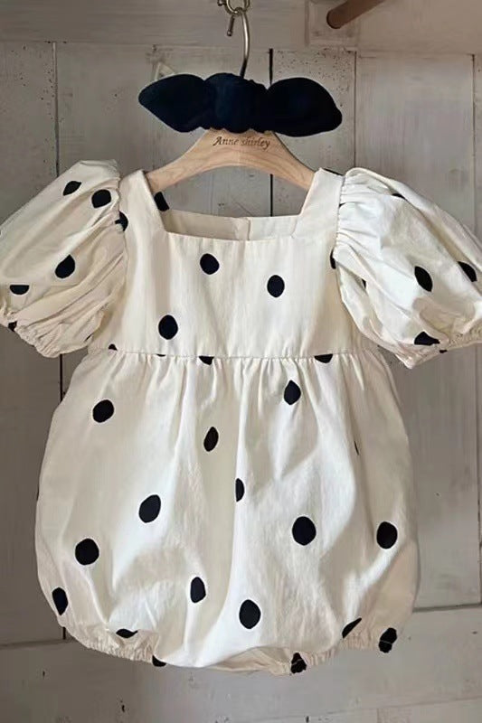 Baby girl wearing a polka dot pattern onesie with square collar and puff sleeves, showcasing a stylish summer outfit.